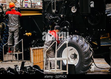 Industrial workers assembles agricultural harvester in workshop. Stock Photo