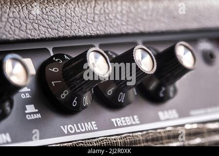 selective focus of the volume, treble and bass control knobs of a guitar amplifier, equalization dials close up, vertical Stock Photo