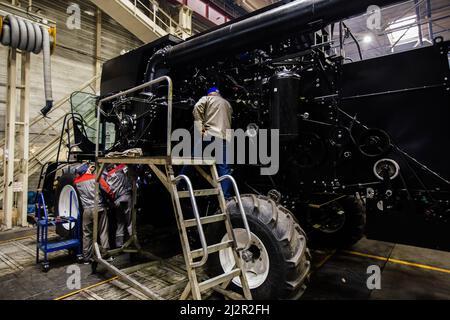 Industrial workers assembles agricultural harvester in workshop. Stock Photo