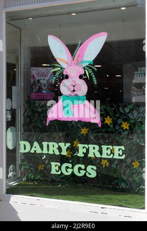 Easter bunny in shop window advertising dairy free eggs, UK Stock Photo