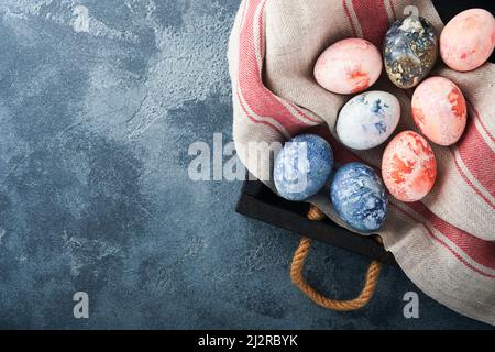 Easter eggs. Dyed Easter eggs with marble stone effect ref and blue color in rustic style on dark stone background. Easter background. Top view. Stock Photo