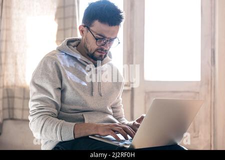 A man with glasses is working on a laptop. Stock Photo