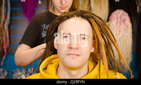 Professional hairstylist makes brown dreadlocks for client Stock Photo