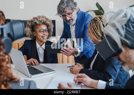Business people using virtual reality goggles work with metaverse tech - VR new technology concept - Focus on african woman face Stock Photo