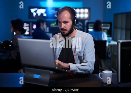 Team of stockbrokers are having a conversation in a dark office with display screens. Professional IT Technical Support Specialist Working on Computer Stock Photo