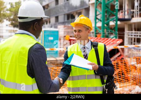 Two engineers concluding agreement and shaking hands Stock Photo