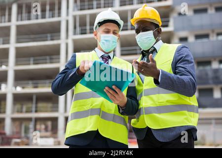 Engineers in masks standing on construction site Stock Photo