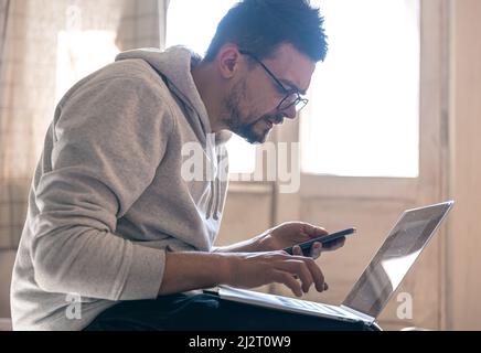 A man with glasses is working on a laptop. Stock Photo