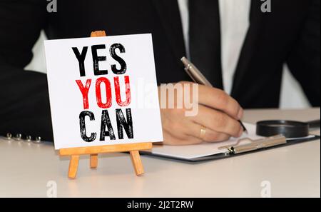 YES YOU CAN. Woman holding blackboard in hands with text YES YOU CAN Stock Photo