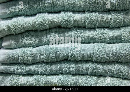 Textured green bath towels stacked close up. Stock Photo