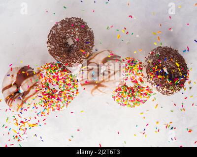 Lots of sweet colorful donuts decorated with icing sugar and chocolate on a white background. Holiday, birthday, sweet calorie food. Supermarket, conf Stock Photo