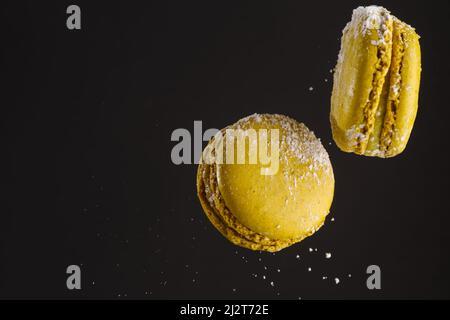 Two yellow french macaroons in a frozen flight on a black background. There are no people in the photo. There is free space to insert. Holiday, birthd Stock Photo