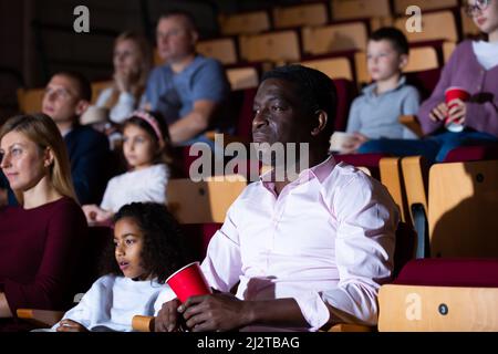 African american man with family watching film in movie theater Stock Photo