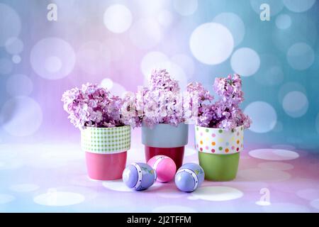 still life of small colorful pots filled with lilacs and sitting behind decorative easter eggs Stock Photo