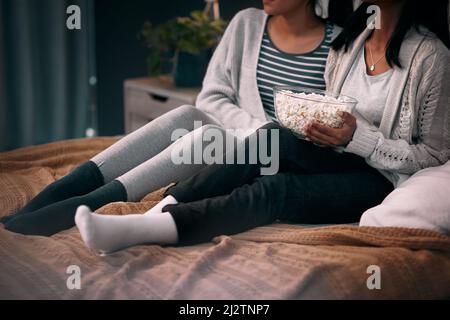 Popcorn and my best friend is just what I need. Cropped shot of two unrecognizable women eating popcorn at home. Stock Photo