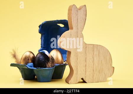 Wooden rabbit and colored eggs on yellow background, Happy Easter card Stock Photo