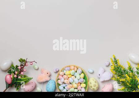 Easter composition. Eggs in a basket, flowering twigs of toy rabbits on a gray background. Flat lay copy space Stock Photo