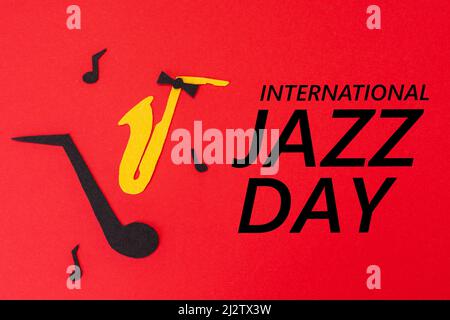 Jazz Day. Silhouette of a saxophone and note with melodies on a red background, cutted out of felt. Flat lay. Stock Photo