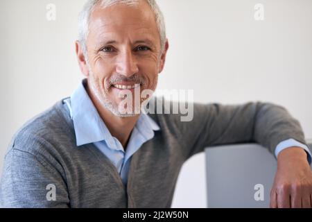 Laid back and confident. Portrait of a mature businessman leaning on his computer in the office. Stock Photo