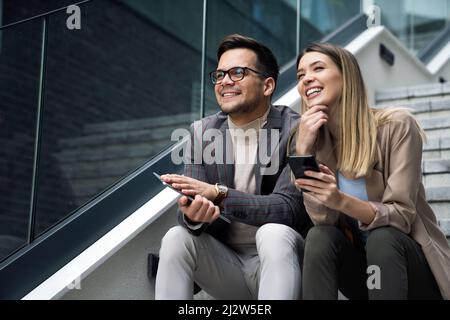 Businessman and businesswoman discussing working together in urban background outdoors. Stock Photo
