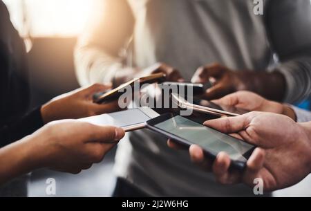 Connecting with a fitness buddy Theres an app for that. Shot of a group of unrecognizable people using their mobile phones together in the gym. Stock Photo
