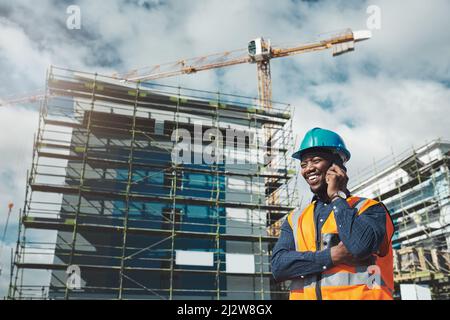 The best building contractor on the block. Shot of a young man using a smartphone while working at a construction site. Stock Photo