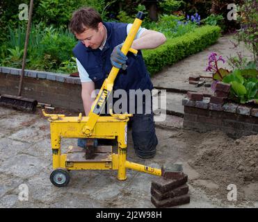 Netherlands - Construction worker cutting tile or stone brick with a special tile cutting machine. Stock Photo