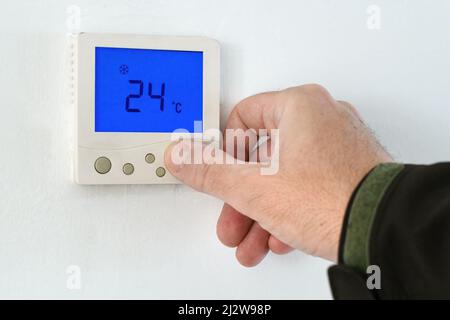 Male hand using of home heating and cooling system control unit, selective focus Stock Photo