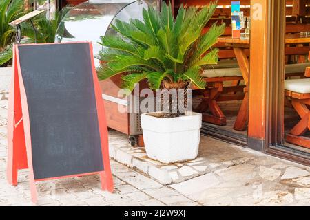 Chalkboard menu black color for text, message or advertising. Mockup is standing near the restaurant on seashore. Sunny day. Stock Photo