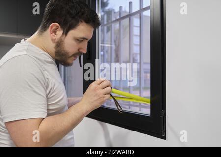 Man measuring window glass to install frosted window vinyl. Stock Photo