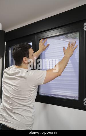 Man installing frosted window vinyl on window glass. Stock Photo