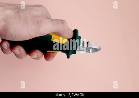 side cutters in hands on a light pink background Stock Photo