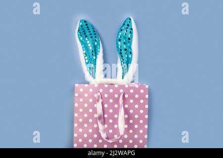 Gift bag with bunny ears. Blue background, copy space. Easter decor. Stock Photo