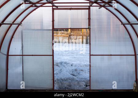 Open door in a winter greenhouse with a lot of snow behind it Stock Photo