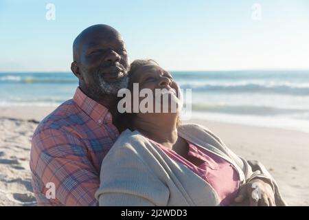 African american senior man embracing retired woman from behind at beach Stock Photo