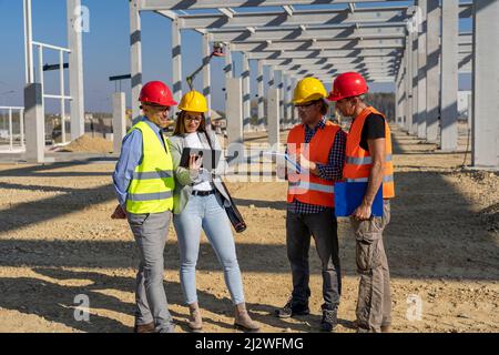 Project Management and Field Crew Meeting on Construction Site. Supervisor, Female Architect , Foreman and Construction Worker Having Conversation at Stock Photo