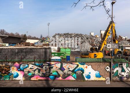 scrap yard with old metal in the district Deutz, in the background the cathedral, wall with graffiti, Cologne, Germany. Schrottplatz mit Altmetall im Stock Photo