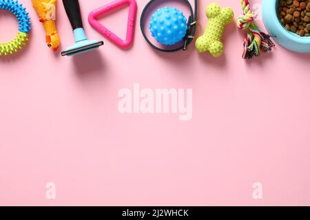 Flat lay composition with pet accessories, toys, dry food bowl on pastel pink table. Pet care and training concept Stock Photo