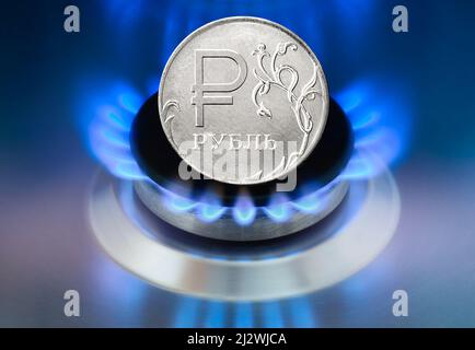 Concept of Russia sanctions of gas payment. Russian Ruble coin and Gas burning in the home stove Stock Photo