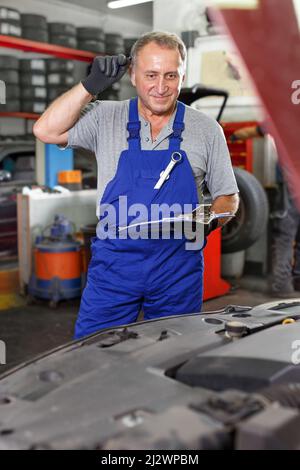 Car mechanic writing job sheet for repairs of vehicle Stock Photo