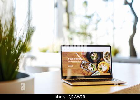 Background image of opened laptop with Food delivery service website set on table in cafe, copy space Stock Photo