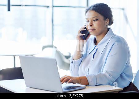 Minimal portrait of young black businesswoman using laptop while working at table in cafe or food court, copy space Stock Photo