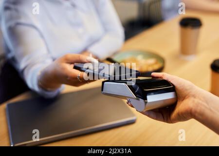 Close up of unrecognizable woman paying with smartphone in cafe and using bank payment machine, copy space Stock Photo