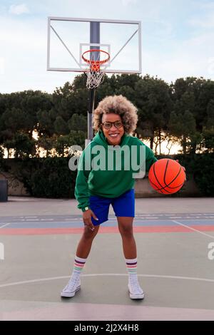 smiling latin woman playing on the basketball court in a city park, concept of urban sport in the street, copy space for text Stock Photo