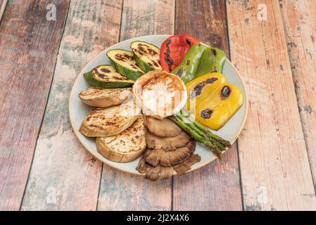 Grilled fresh vegetables from the garden with salt and oil. Assortment of peppers, mushrooms, goat cheese, green asparagus and zucchini Stock Photo