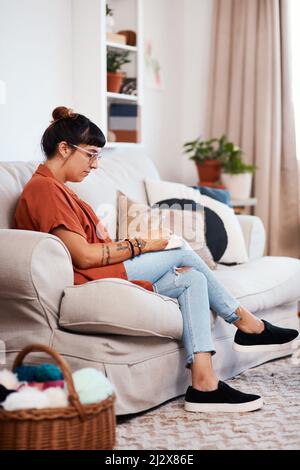 About todays diary entry.... Shot of an attractive young woman drawing while relaxing on the sofa at home. Stock Photo
