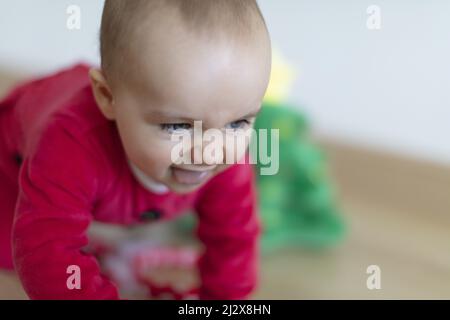 Baby girl wearing Santa's crawling with incredibly determined facial expression. First Christmas Stock Photo