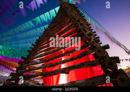 festa junina decoration in brazil with giant bonfire and colorful flags Stock Photo