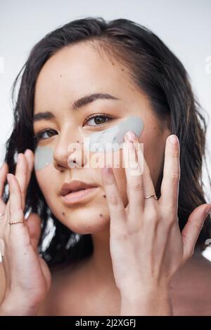 Soap and water is just not enough. Studio shot of a beautiful young woman wearing under-eye patches. Stock Photo