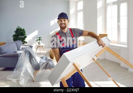 Happy young truck delivery or moving company worker carrying furniture and smiling Stock Photo